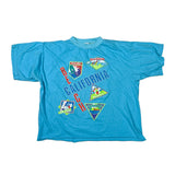 A vintage bright blue short-sleeve t-shirt laid flat on a white background, featuring 'BEE CHALNG CALIFORNIA' text and several colorful retro-style graphics.