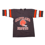 A vintage Cleveland Browns football jersey laid flat on a white surface. The dark brown V-neck jersey features orange and white striped sleeves and a large orange helmet graphic with 'CLEVELAND BROWNS' in orange arched lettering on the front.