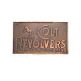 Bronze belt buckle with 'Colt Revolvers' text and horse logo on a white background