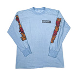 A light blue long-sleeve t-shirt with 'Hershey's' printed in a black box logo on the chest, and 'watchamacallit' in orange and red stylized text running down both sleeves, laid flat on a white background.