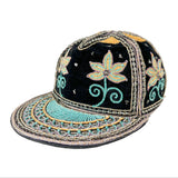 A black velvet baseball cap with intricate turquoise, gold, and silver embroidery, featuring floral motifs and a decorative embroidered brim.