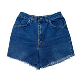 A pair of high-waisted, raw-edge denim shorts in a classic medium blue wash, laid flat on a light off-white background.