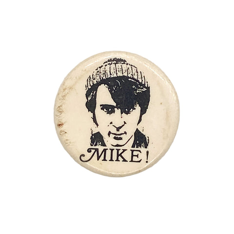 Button badge with a black and white illustration of a person wearing a beanie and the word 'MIKE!' below on a white background.
