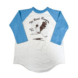 Baseball shirt with blue sleeves and white body, featuring 'The Road Runner' graphic on a light gray background.