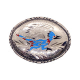 An oval silver-toned metal buckle featuring a hand-painted blue, red, and black bird design with engraved floral details and a braided border.