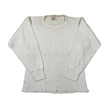 An off-white waffle knit long-sleeve shirt laid flat on a light gray background.