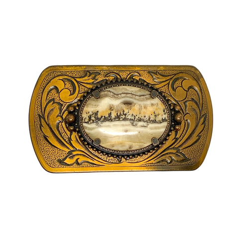 Decorative belt buckle with intricate design and central scene on a white background