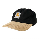 A Carhartt 6-panel baseball cap featuring a black crown and a light tan curved brim, with the signature Carhartt logo patch on the front.