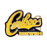 A Cariboo Brewing logo enamel pin featuring yellow script lettering with black outlines and 'BREWING' in yellow block letters on a black background, shown on a white textured surface.