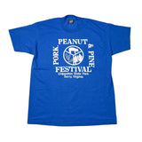 A blue short-sleeve t-shirt laid flat on a white background, featuring a white graphic print that reads 'PORK & PINE PEANUT FESTIVAL' with 'Chippokes State Park Surry, Virginia' below.