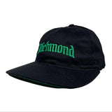 Black cap with green embroidered text on a white background