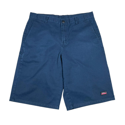 A pair of blue cotton shorts laid flat on a white background, featuring a button closure, belt loops, and a small red and white Dickies brand patch on the lower left leg.