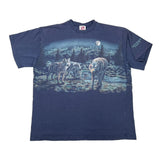 A navy blue short-sleeve graphic t-shirt laid flat on a white background, featuring a large front print of three wolves in a moonlit forest scene. The shirt has a red and white neck label and a small graphic on the right sleeve.