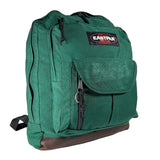 A green Eastpak backpack with a brown leather-like base and black zippers, shown on a white studio background.