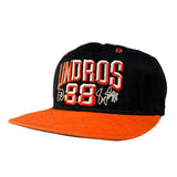 A black and orange snapback cap featuring 'LINDROS 88' embroidered on the front in red and white, with a bright orange flat brim.