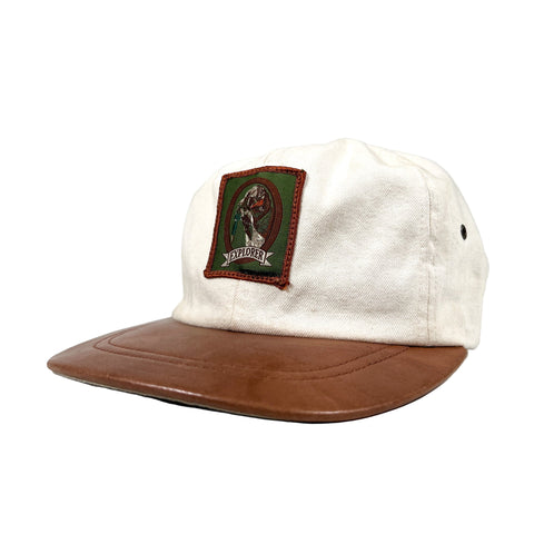 White cap with brown visor and green patch on a white background