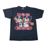 A vintage black graphic t-shirt featuring Magic Johnson and Larry Bird from the 1995 Double USA Basketball Final. The graphic shows both players in their national team uniforms holding basketballs, with 'DOUBLE USA ATHLET 15' and an American flag design in the background.