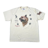 An off-white short-sleeve graphic t-shirt featuring a detailed illustration of a Norwich Terrier dog, black paw prints, and text on the front, laid flat on a light gray background.