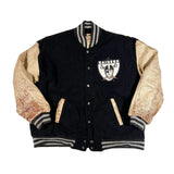 Black letterman jacket with gold sleeves featuring a logo on a white background