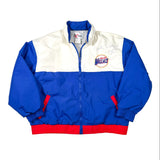 A vintage blue, white, and red windbreaker jacket from the Vancouver Canucks NHL team, featuring a white and blue color-blocked design with a red hem and cuffs, autographed on the chest, and displayed flat on a white background.