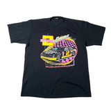 A black short-sleeve graphic t-shirt laid flat on a white background, featuring a colorful racing design with a race car, checkered circle, and text including 'Dueling Deuce'.
