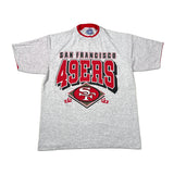 A light gray heather short-sleeve t-shirt featuring the San Francisco 49ers logo on the front, laid flat against a light off-white background.