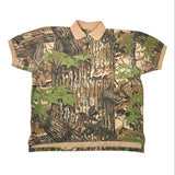A short-sleeve polo shirt with a woodland camouflage pattern featuring tree bark, leaves, and green foliage. The collar, sleeve cuffs, and hem are solid tan/beige.
