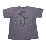 A faded purple short-sleeve t-shirt with a large green and black dollar sign graphic on the front, laid flat on a white fabric background.