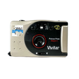 A vintage Vivitar Focus Free PN2011 compact film camera with a beige and black body, featuring a red ring around the lens and a 'Vivitar' logo on the front.