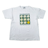 A white short-sleeve t-shirt laid flat on a light gray surface, featuring a Wimbledon-themed graphic with tennis balls in a grid and the text 'WIMBLEDON THE CHAMPIONSHIPS'.