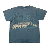 A faded blue-gray short-sleeve t-shirt featuring a graphic print of a pack of wolves in a dark forest on the front, laid flat on a white background.