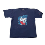 A navy blue short-sleeve t-shirt laid flat on a white fabric background, featuring a central graphic of a white bear wearing a red Santa hat and holding a red Santa bag, with 'SANTA CLARA' printed below.