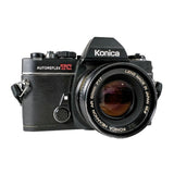 A vintage Konica AF M40 film camera with a black TC 50mm lens, photographed on a light gray textured background.