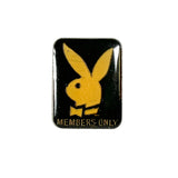 A vintage Playboy bunny enamel pin with a black background and gold lettering that reads 'MEMBERS ONLY', displayed on a textured white surface.