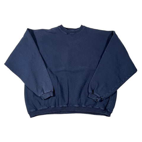 Folded navy blue sleeveless shirt on a white surface with a colorful patterned rug in the corner.