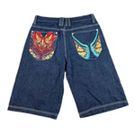 Blue denim shorts with colorful designs on the pockets against a white background