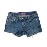 A pair of medium-wash blue denim cut-off shorts with frayed hems, laid flat on a light gray background.
