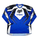 A long-sleeve motocross jersey laid flat on a white surface. The jersey is royal blue with black, white, and gray graphic panels, featuring the Fox Racing and Yamaha logos on the chest and sleeves.