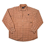A long-sleeve plaid button-up shirt in orange and brown, laid flat on a white background. The shirt features two chest pockets with button closures, a classic collar, and buttoned cuffs.