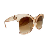 Oversized round sunglasses with a translucent peach-pink acetate frame and brown gradient lenses, shown on a clean white background.