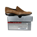 Brown suede loafer on a Prada shoe box against a white background