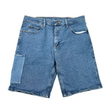 A pair of medium-wash blue denim shorts with a large patch pocket on the left leg, laid flat on a white background.